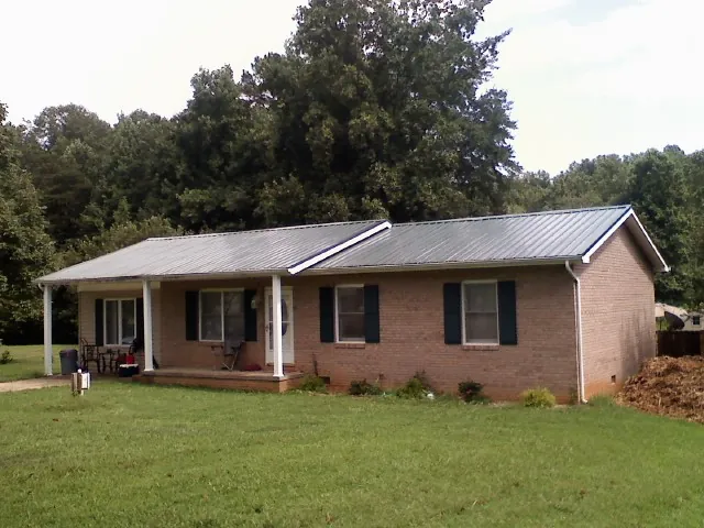 Gray metal roof on a brick ranch house with a side carport in Sebastian