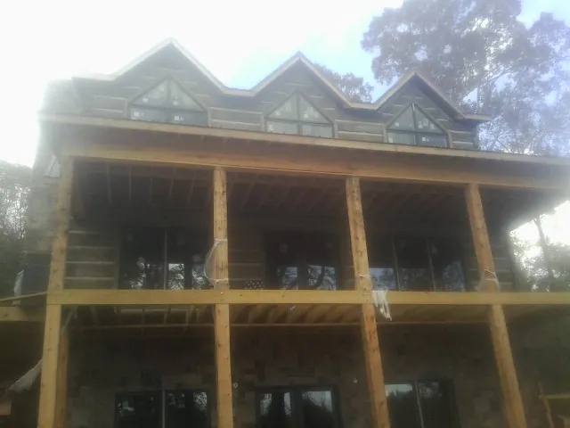 Dormers and porch framing on a large log home under construction — Roof Coating work by our crew in Sebastian