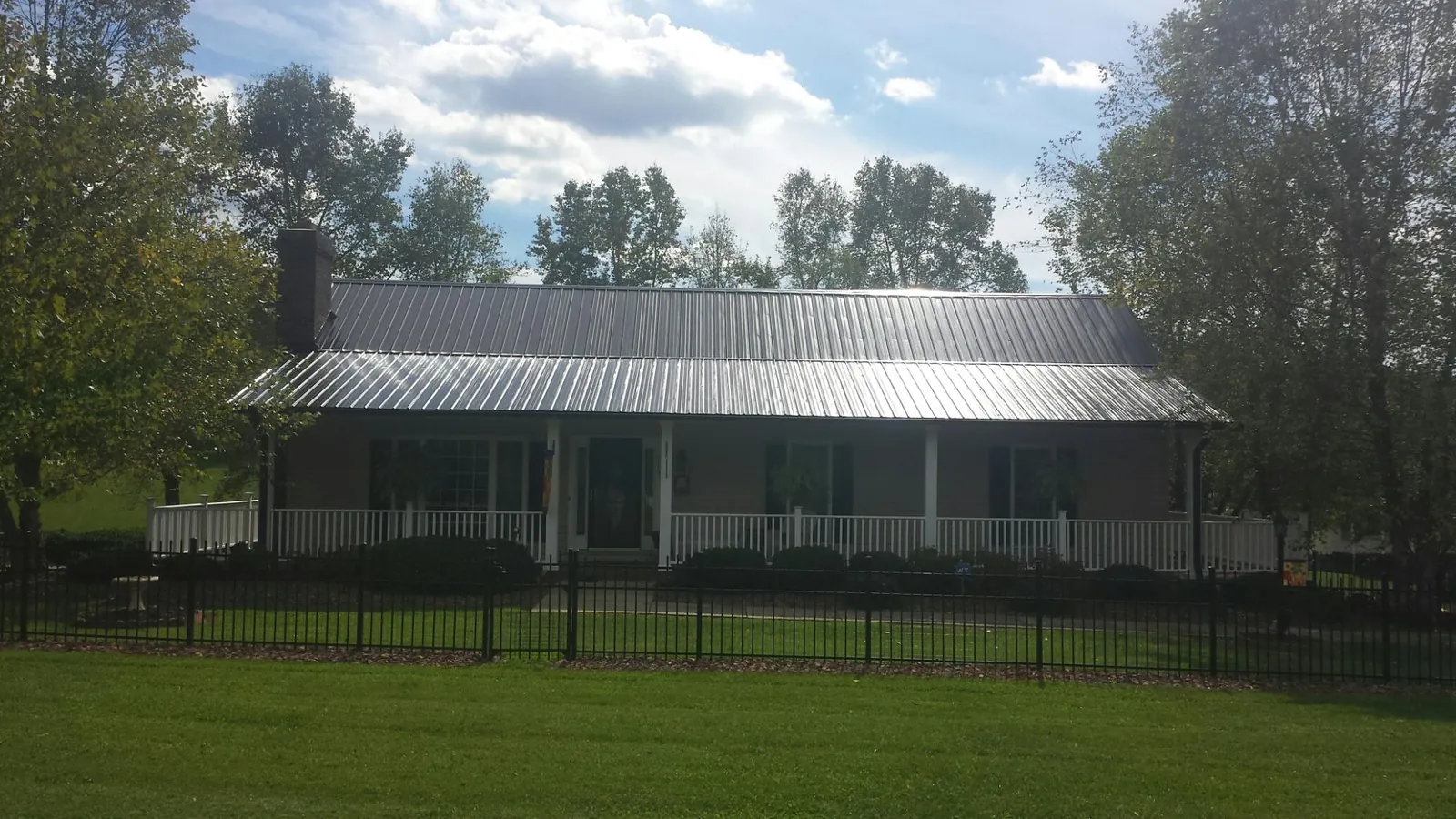 Gray metal roof on a brick ranch with a full width front porch — Gutter Guard Installation work by our crew in Sebastian