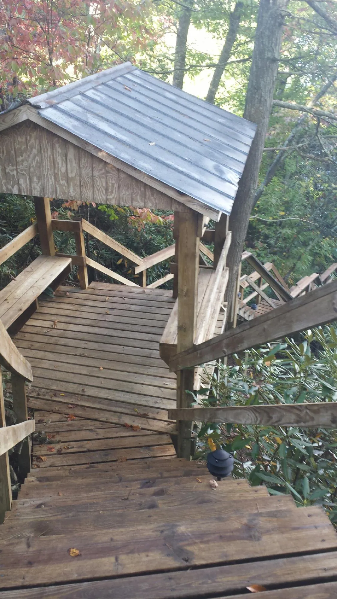 Metal roofed shelter over wooden steps on a wooded walkway — Skylight Repair & Installation work by our crew in Sebastian