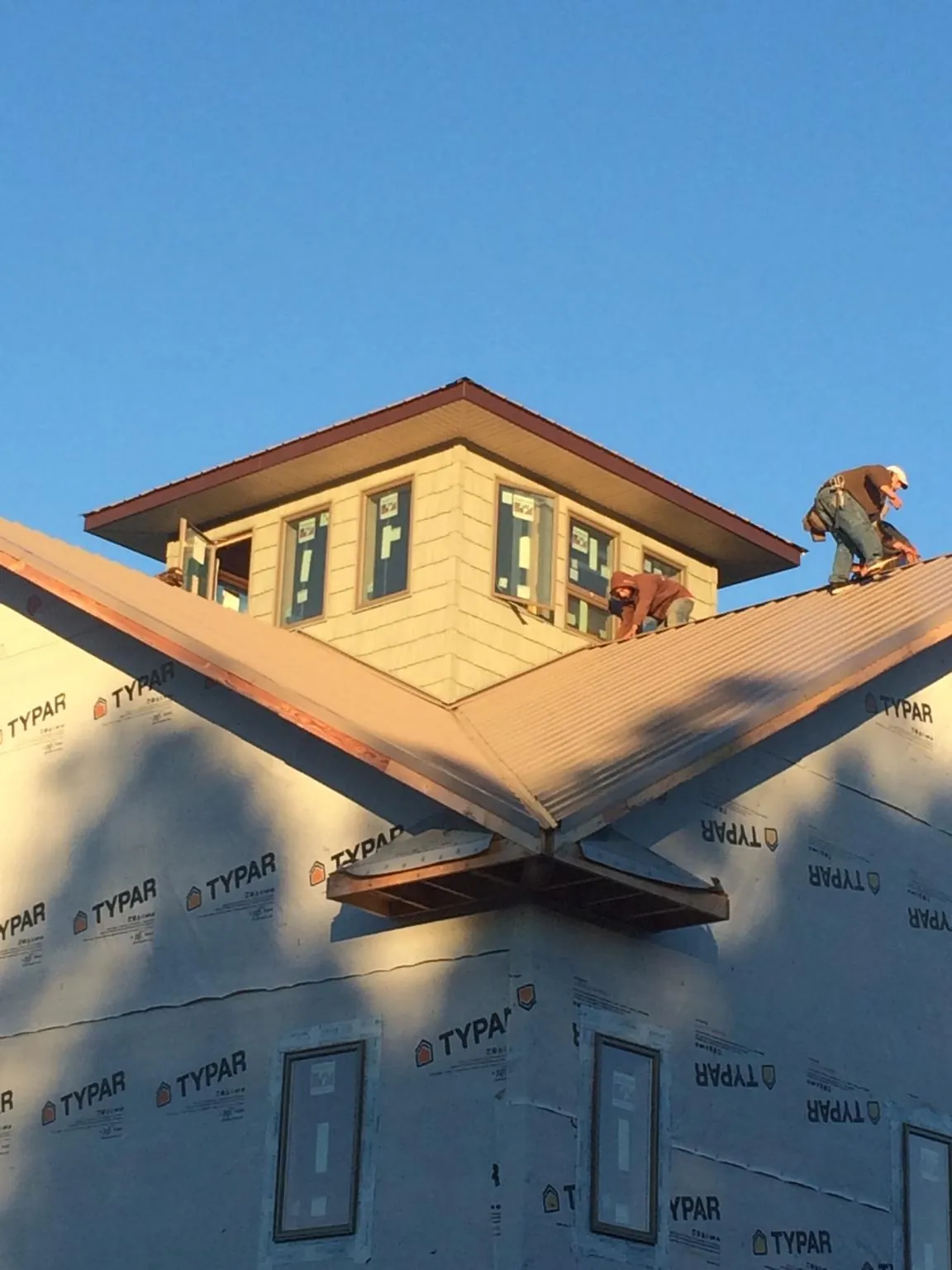 Roofers working around a rooftop cupola on a new metal roof at sunset — Roof Waterproofing in Sebastian by Roofing Brothers